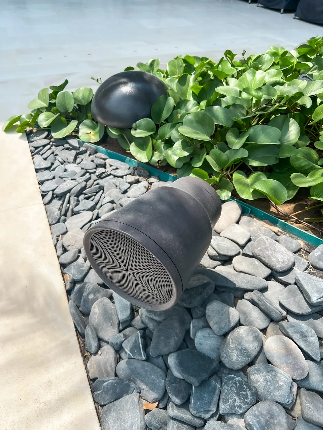 Parlante de exterior instalado sobre piedras en el jardín