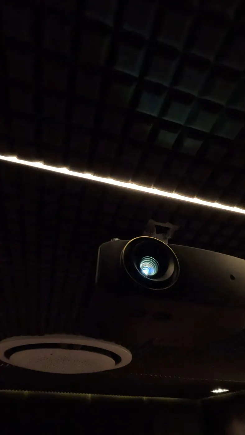 Proyector instalado en sala de cine con paneles acústicos en techo