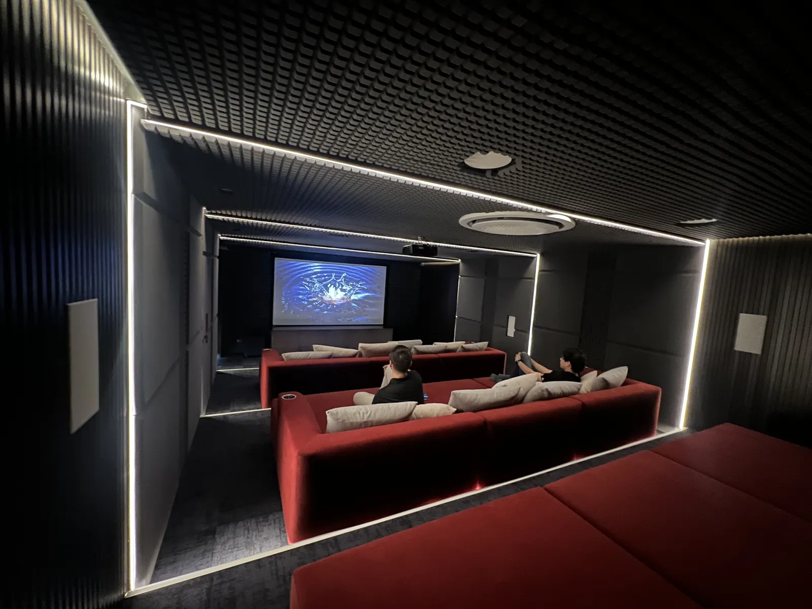 Cine privado con pantalla de proyección, butacas rojas y acústica tratada, integrado por Biosystem